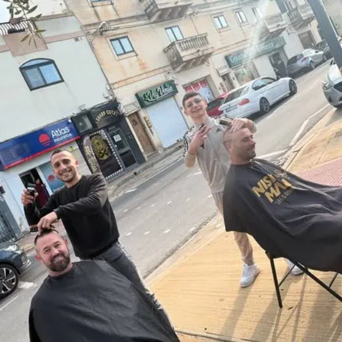 Sharp Cutz barbers cutting hair outside the Rabat shop during a scheduled power outage